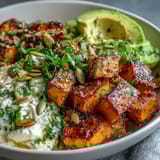 Roasted sweet potatoes with crispy edges and creamy avocado in a Hot Honey Sweet Potato Bowl.