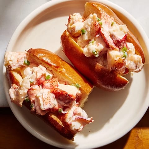 Buttery New England Lobster Roll with warm lobster meat, fresh lemon juice, and chives, served with crispy potato chips.