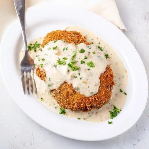 Crispy breaded chicken fried steak with rich peppery gravy, ready to serve alongside green beans.