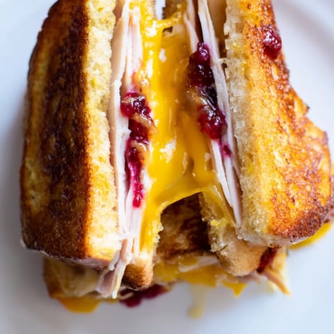 A close-up of the Smoked Turkey Grilled Cheese reveals gooey cheese and a crispy, buttery crust.