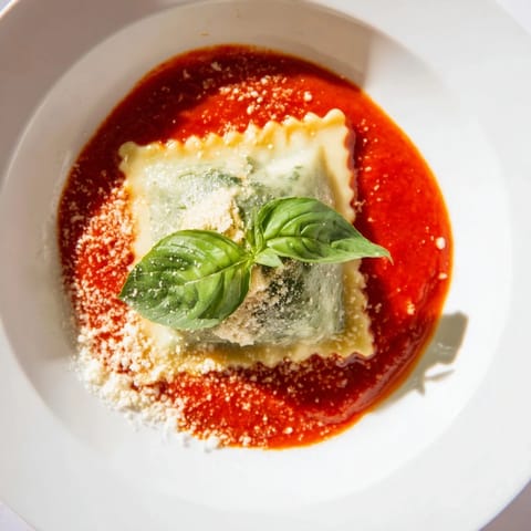 A close-up of tender ravioli filled with creamy ricotta and spinach, swimming in a rich, garlicky marinara sauce.