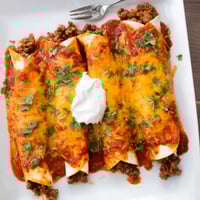 Golden baked Beef Enchiladas filled with seasoned ground beef, cheese, and rich red sauce, served with sour cream.