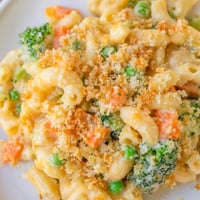 Golden-brown baked Garden Veg Mac and Cheese in a casserole dish, filled with peas, broccoli, and carrots.