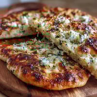 Warm, pillowy The Best Easy Garlic Naan Bread fresh from the skillet, brushed with melted butter and minced garlic.
