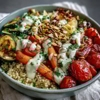 Freshly roasted bell peppers, zucchini, and carrots sit atop fluffy quinoa in a healthy Roasted Vegetable Quinoa Bowl, ready to eat.